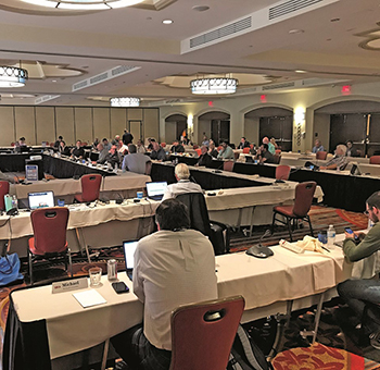 A group of people spaced out in a meeting room from the San Antonio open quarterly meeting.