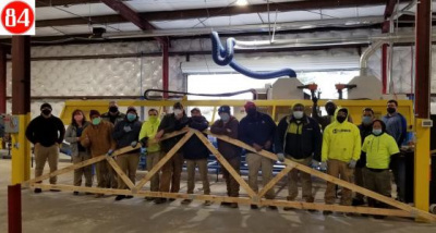Group of 84 Lumber employees holding a roof truss