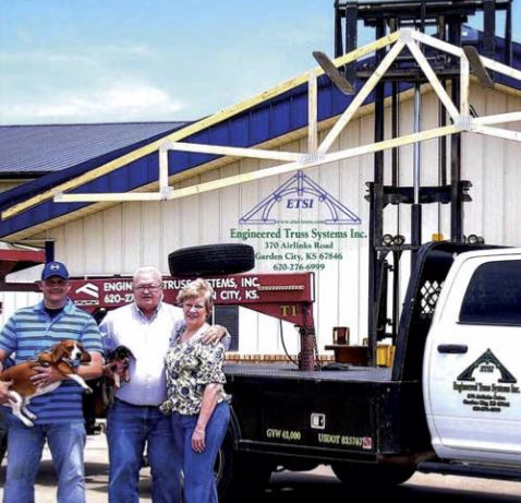 Justin standing outside of Engineered Truss Systems holding his dog