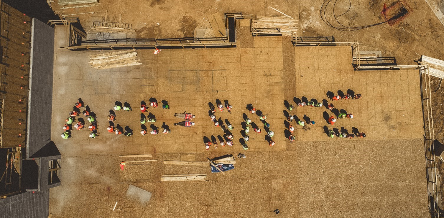 Birds-eye view of people standing to form the words ace = safe