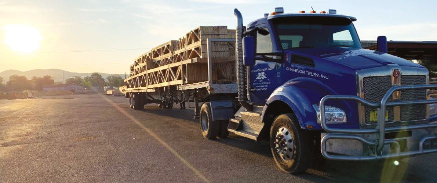 Champion Truss trailer parked in a lot ready to haul stacks of trusses